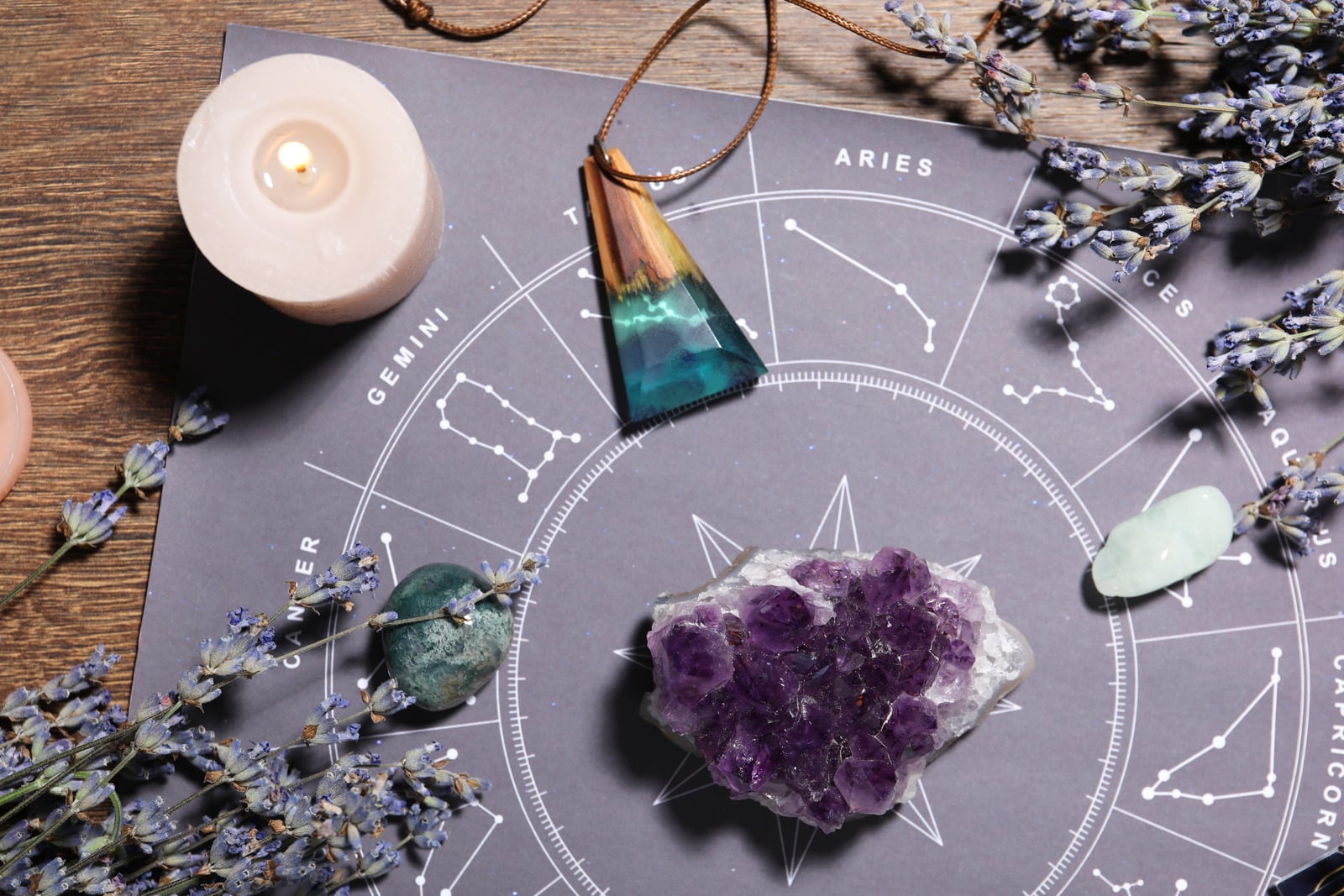 An astrology chart with an amethyst crystal, candle, and lavender from Jordan Everly's reading practice